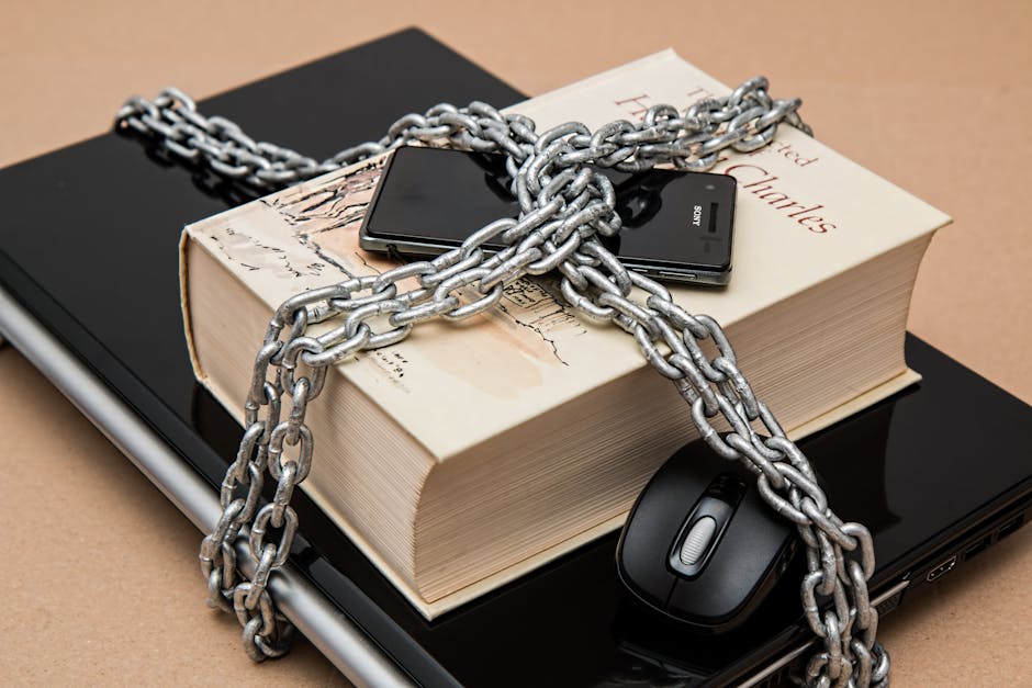 Celular seguro: 7 dicas para proteger seu dispositivo agora! Chain-locked book, phone, and laptop symbolizing digital and intellectual security.