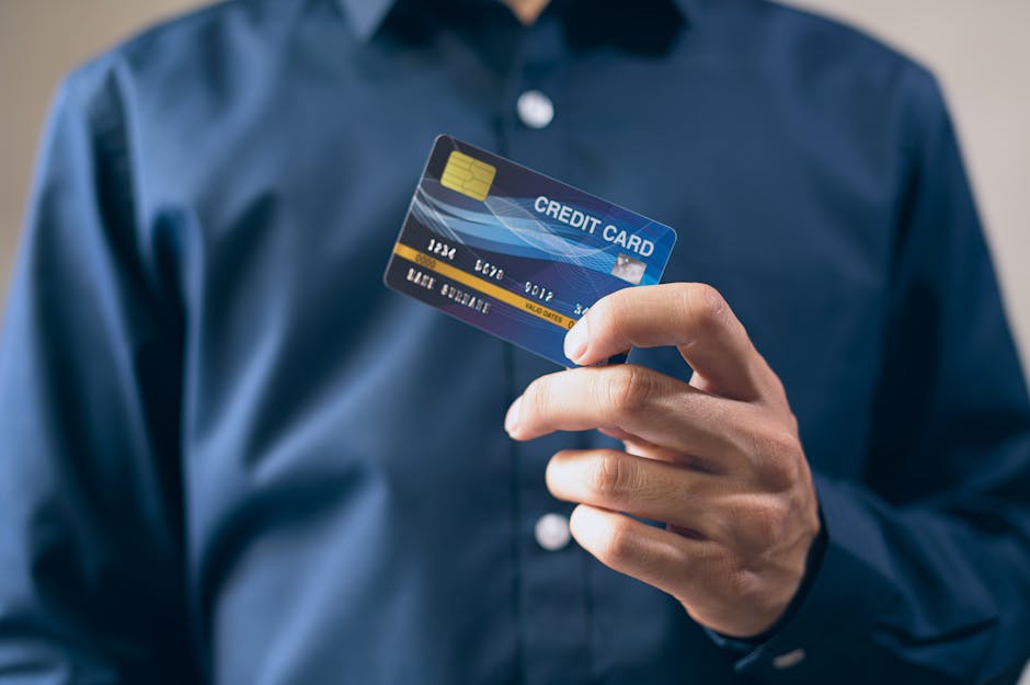 Como aumentar limite do cartão de crédito sem tarifa facilmente? Close-up of a person holding a credit card in a hand, wearing a button-up shirt.